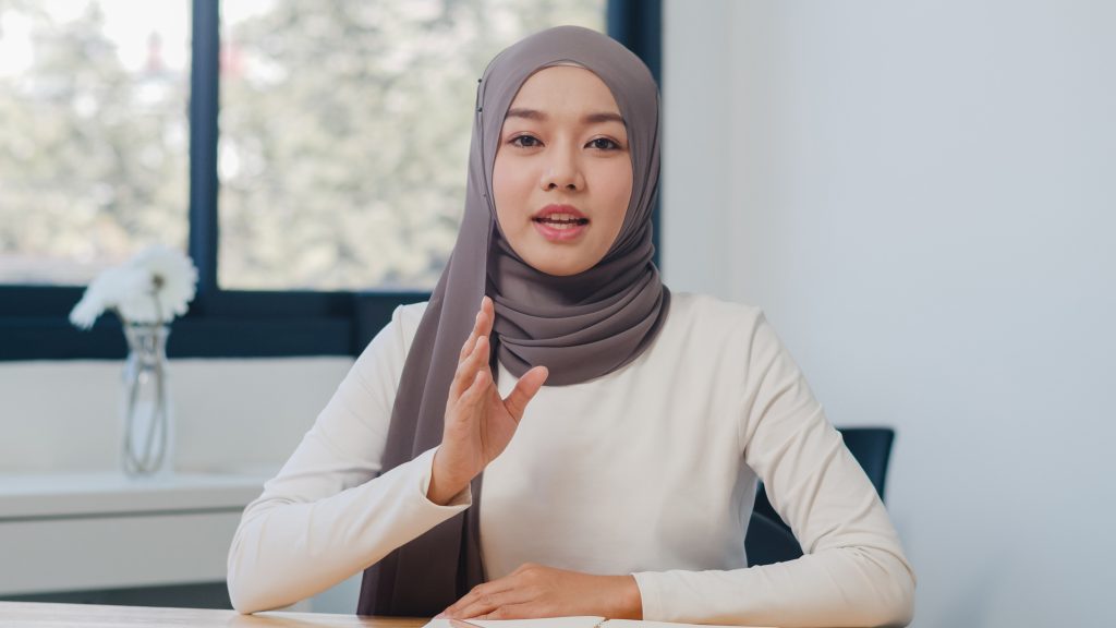 Asia muslim lady looking at camera talk to colleagues about plan in video call in new normal office. Working from home, remotely work, self isolation, social distancing, quarantine for coronavirus.